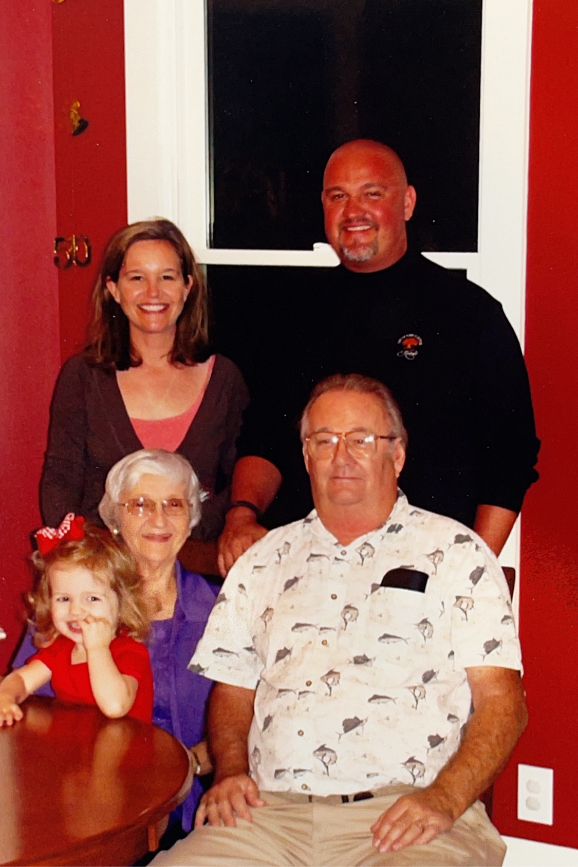 A family portrait at home spanning three generations, gathered around a table